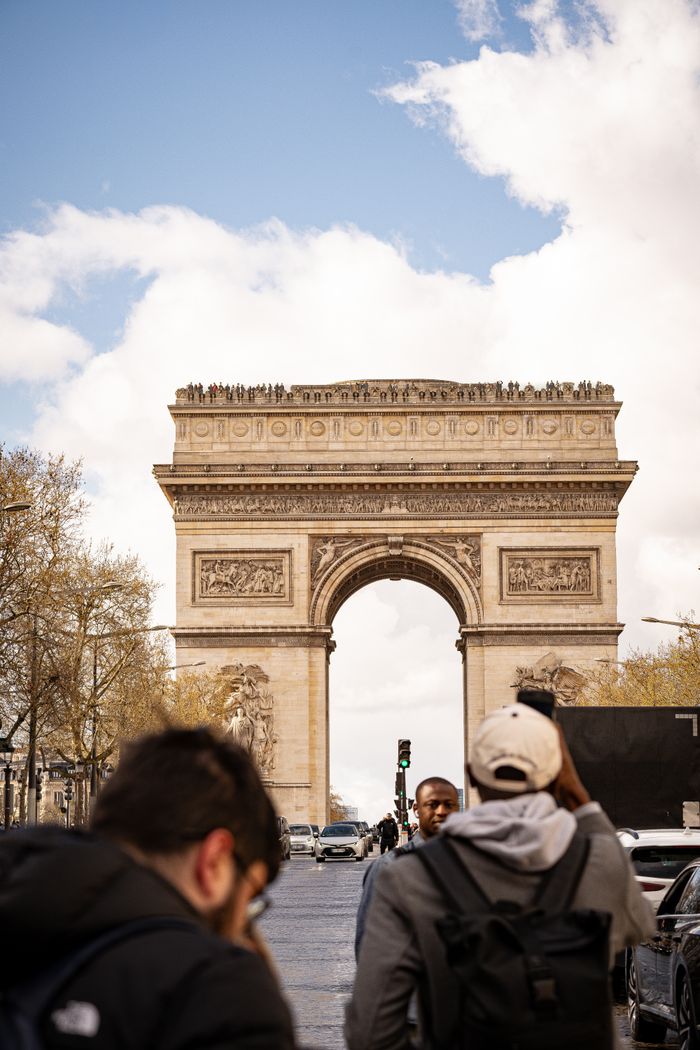 The Art of Drawing Readers In: Your attractive post title goes here Iconic Arc de Triomphe in Paris with people and vehicles in view, showcasing urban life.
