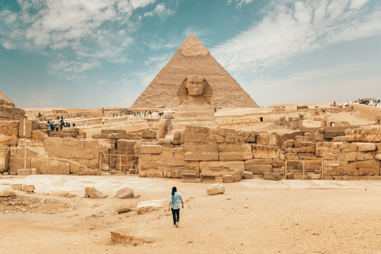 Mastering the First Impression: Your intriguing post title goes here Back view of unrecognizable man walking towards ancient monument Great Sphinx of Giza